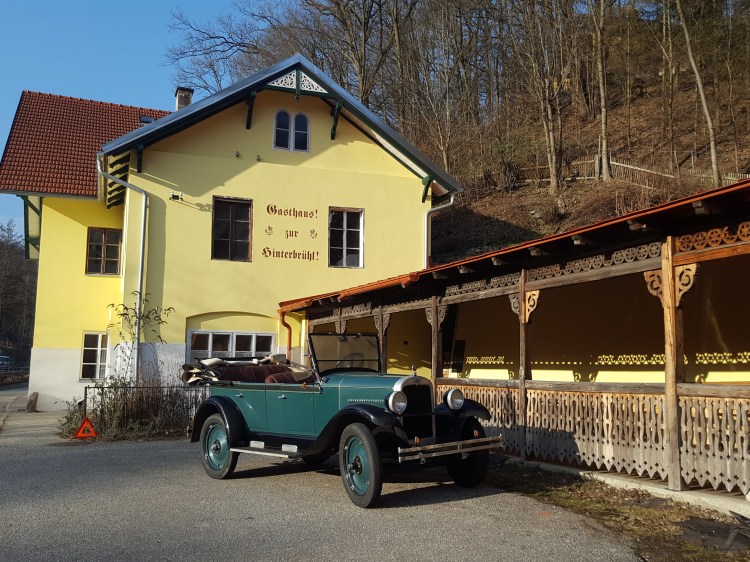 Ehemaliges Gasthaus zur Hinterbrühl in Marbach an der Donau mit historischer Veranda und Oldtimer vor dem Gebäude.