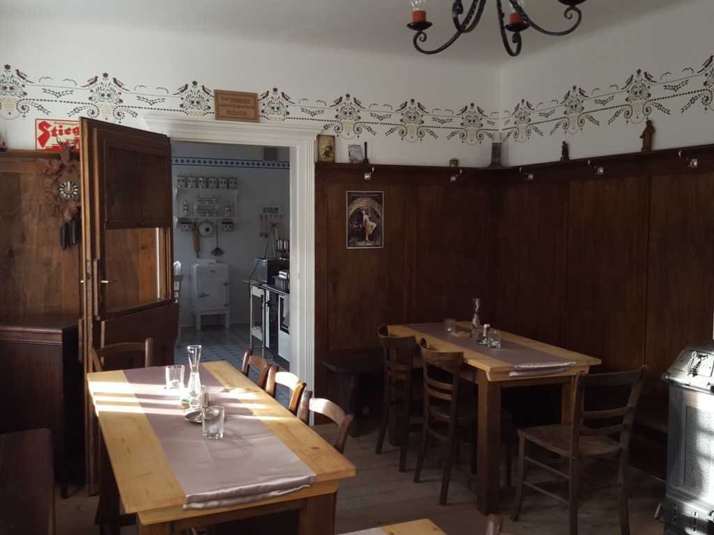 Kleine Gaststube mit Blick durch die geöffnete historische Küchentüre mit Durchreiche in die Küche; die Tür kam bereits bei Dreharbeiten zu „Vampir auf der Couch“ zum Einsatz.