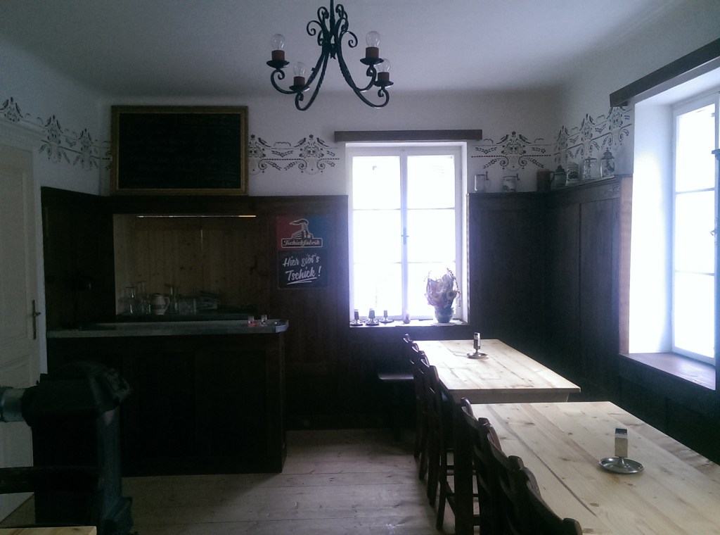 Kleine Gaststube im ehemaligen Gasthaus zur Hinterbrühl mit historischer Holzlamperie, Schank und Wirtshausmöblierung.